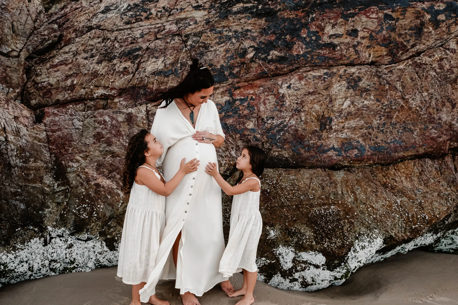 Pregnant mum with daughters touching her belly
