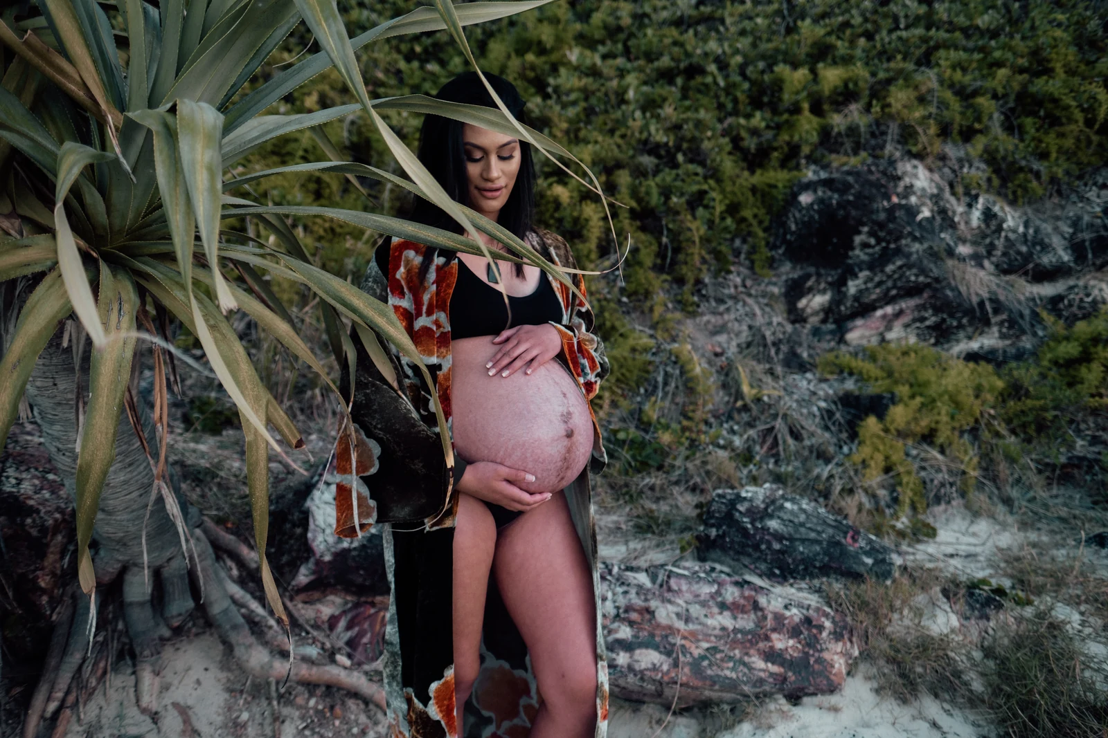 Terina cradling her bump beside flax