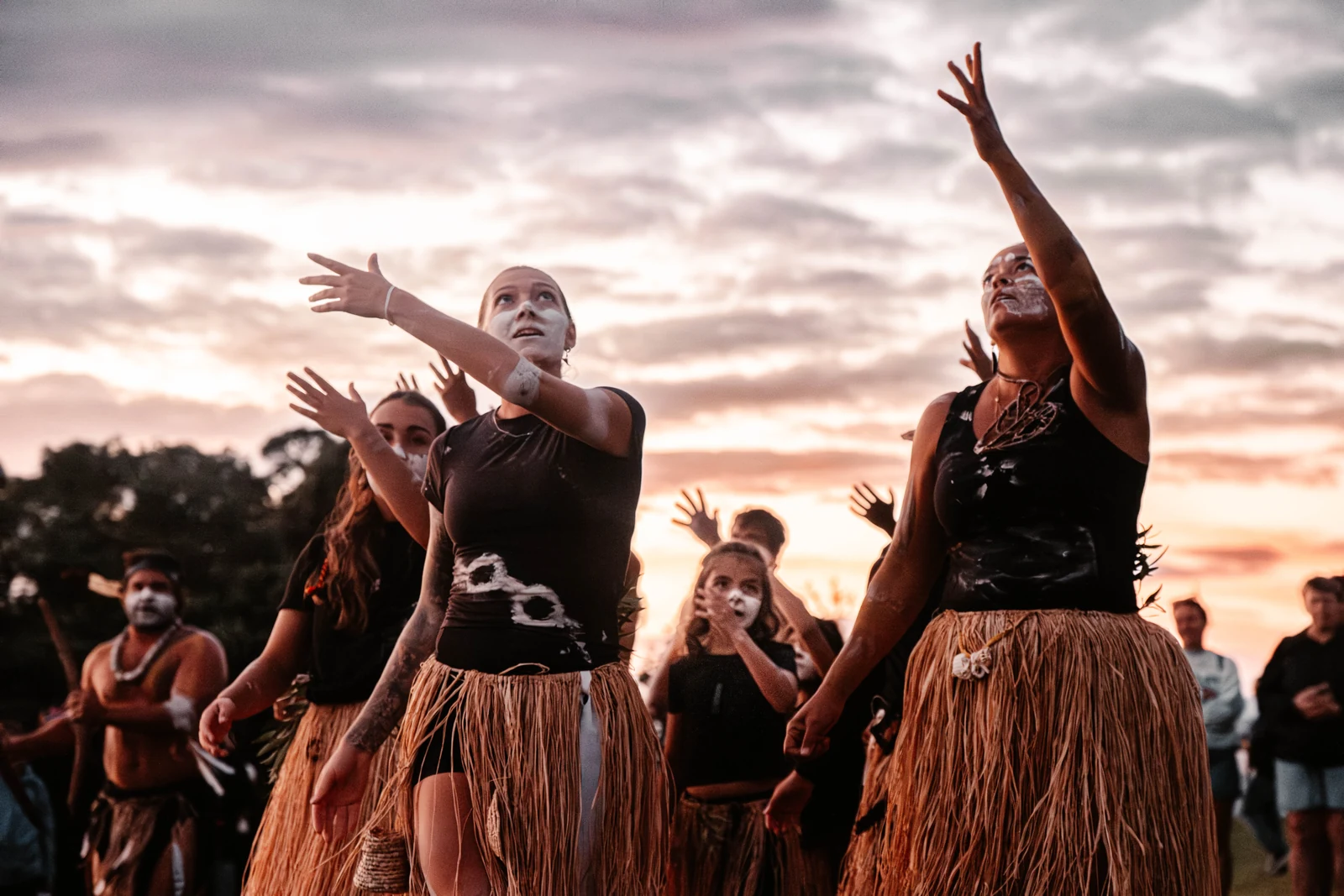 Aboriginal dancers performing at Waitangi Day beneath a sunset sky